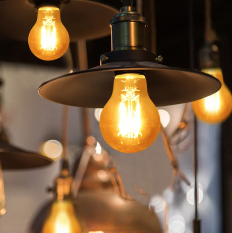 Aigostar 8W E27 gloeilamp amber glas die sfeervol warm licht uitstraalt in een moderne hanglamp.