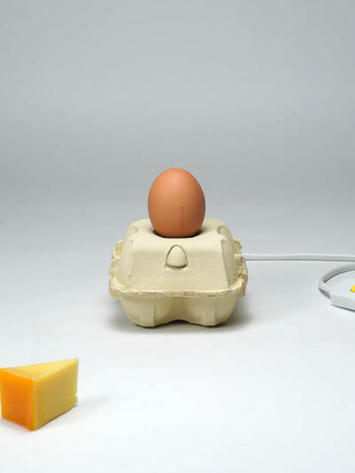 Nachhaltige LED-Lampe EggboxLAMP mit einem Ei in einem Kartonhalter, perfekt für nachhaltige Beleuchtung