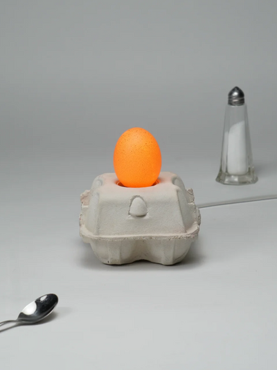EggboxLAMP Classic LED-Lampe mit orangefarbenem Licht in einem Eierkarton mit Löffel und Salzstreuer