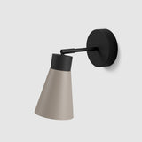 Moderne wandlamp van Studio Monton met een beige lampenkap en een zwart bevestigingspunt